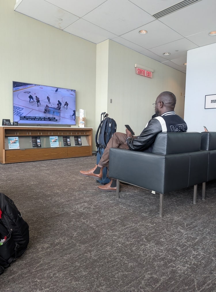 seating with view of TV showing hockey and PressReader magazine information.