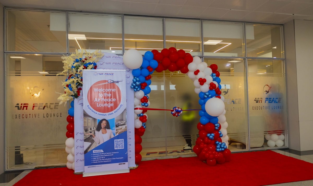 Entrance to the Air Peace lounge with balloons and a red carpet, and a sliding door for entrance into the lounge.