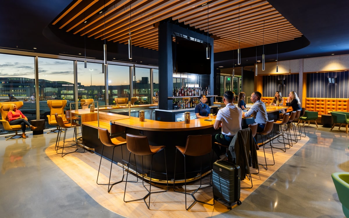 Bar area with seating and people, and large windows in the background.