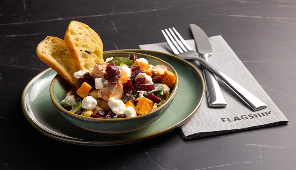 Flagship Lounge menu item of a salad with chicken and fruit with silverware.
