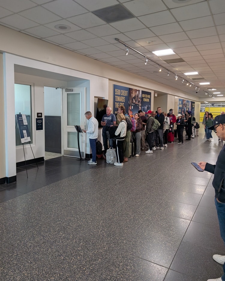 people waiting to get into the Aspire Lounge, in a long hallway.