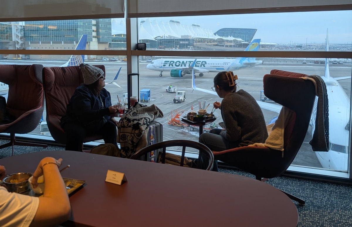 chairs and tables along the floor-to-ceiling windows with a view of the ramp and planes in the background.