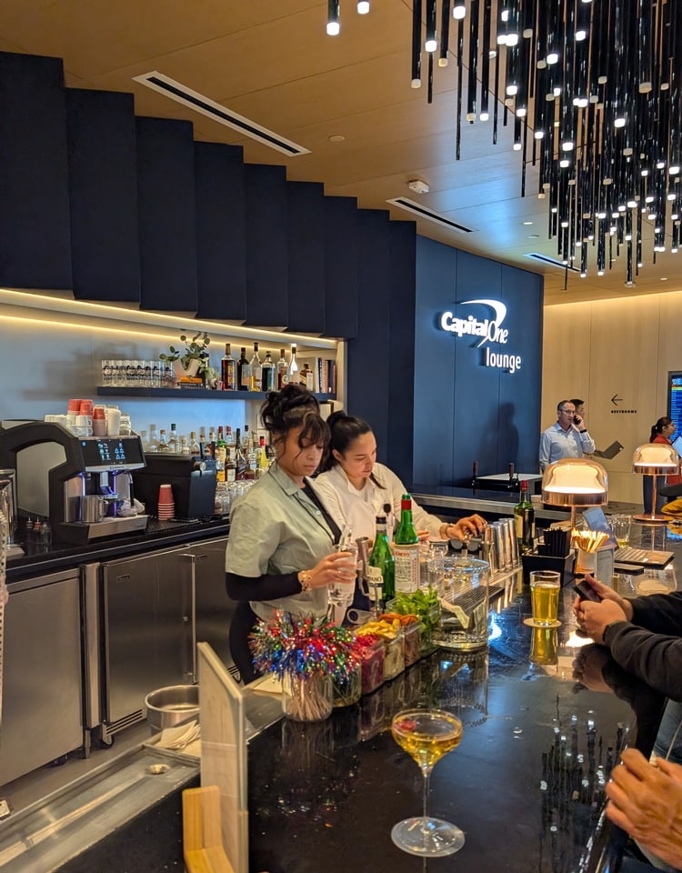 bar area with people sitting at the bar and employees making drinks.