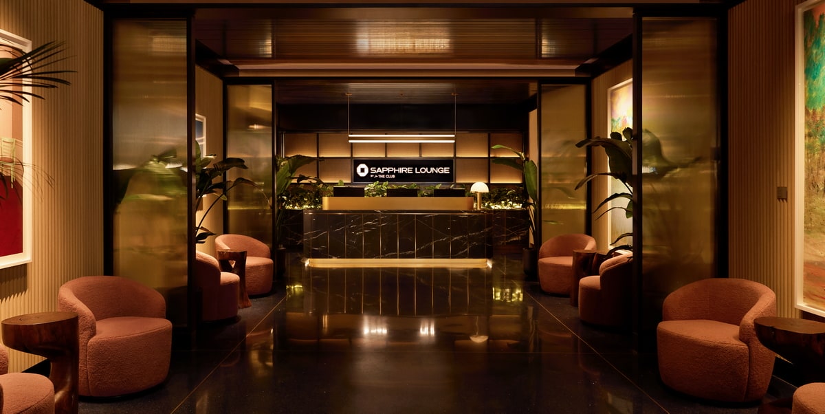 entrance into lounge with chairs and seating along corridor, and a reception desk.
