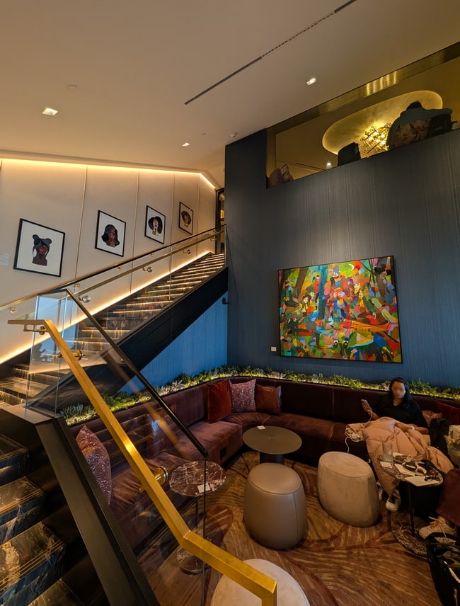sofa area next to the stair case with art hanging in the background.