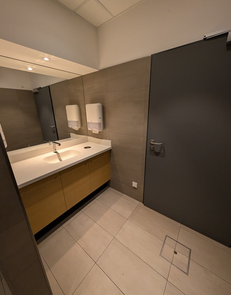 mens restroom showing the sink area, paper towlels and mirrors.