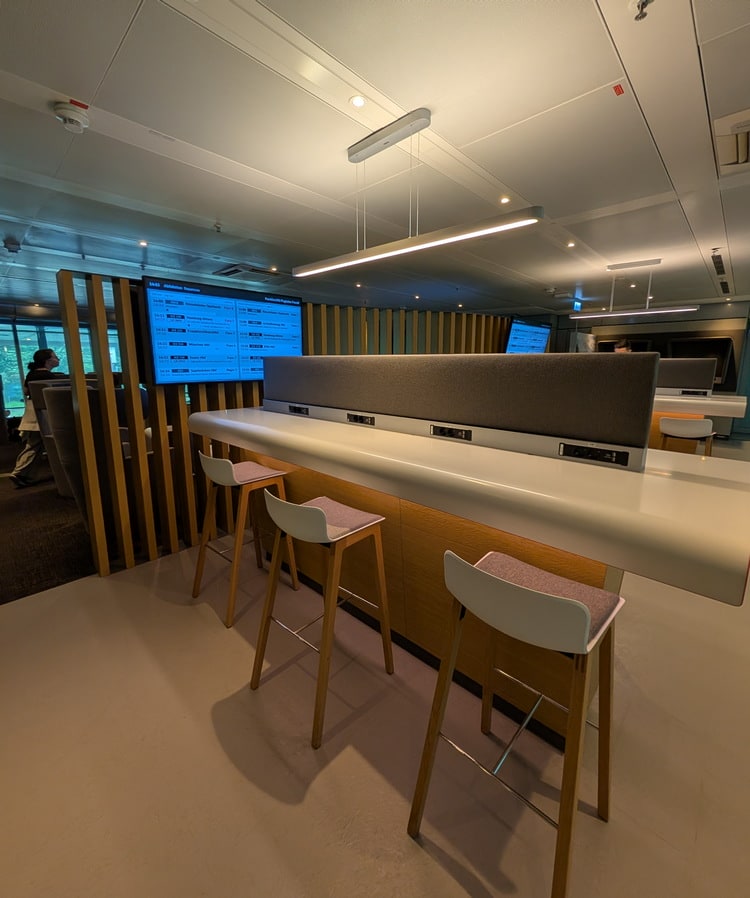 work area with high top tables, charging plugs, and TV.