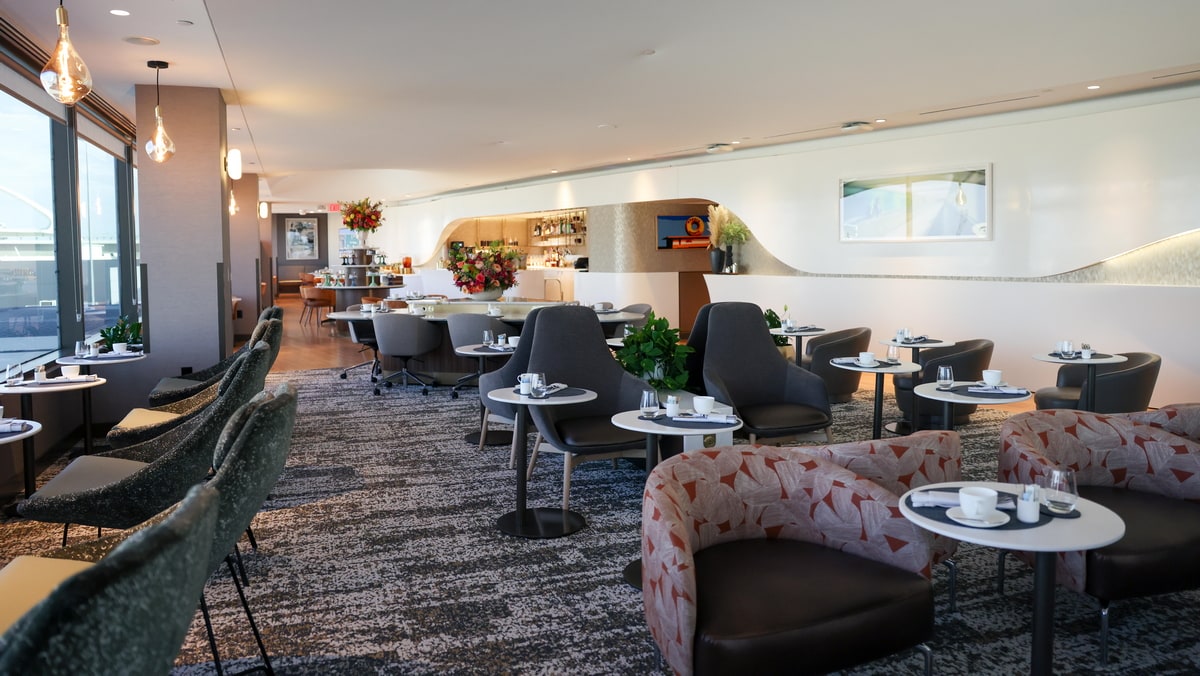 Seating and tables inside of the Delta One lounge with large windows on the side.