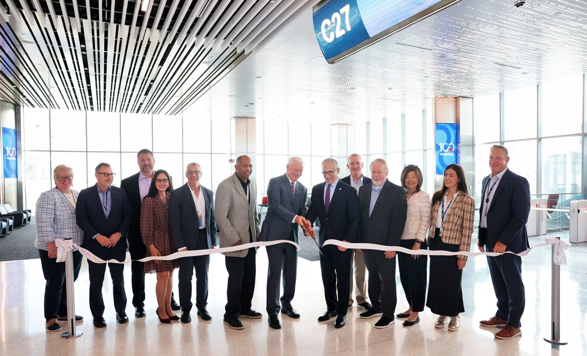 Ribbon cutting in the section of Terminal C at DFW with 13 people behind a ribbon.