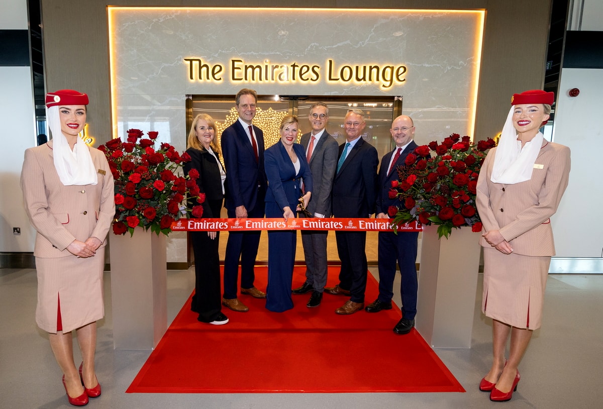 people standing outside of the Emirates lounge for a ribbon cutting on a red carpet.