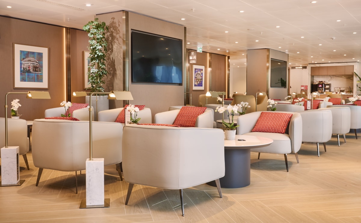 seating area with tables and chairs, TVs and hallway in the background.