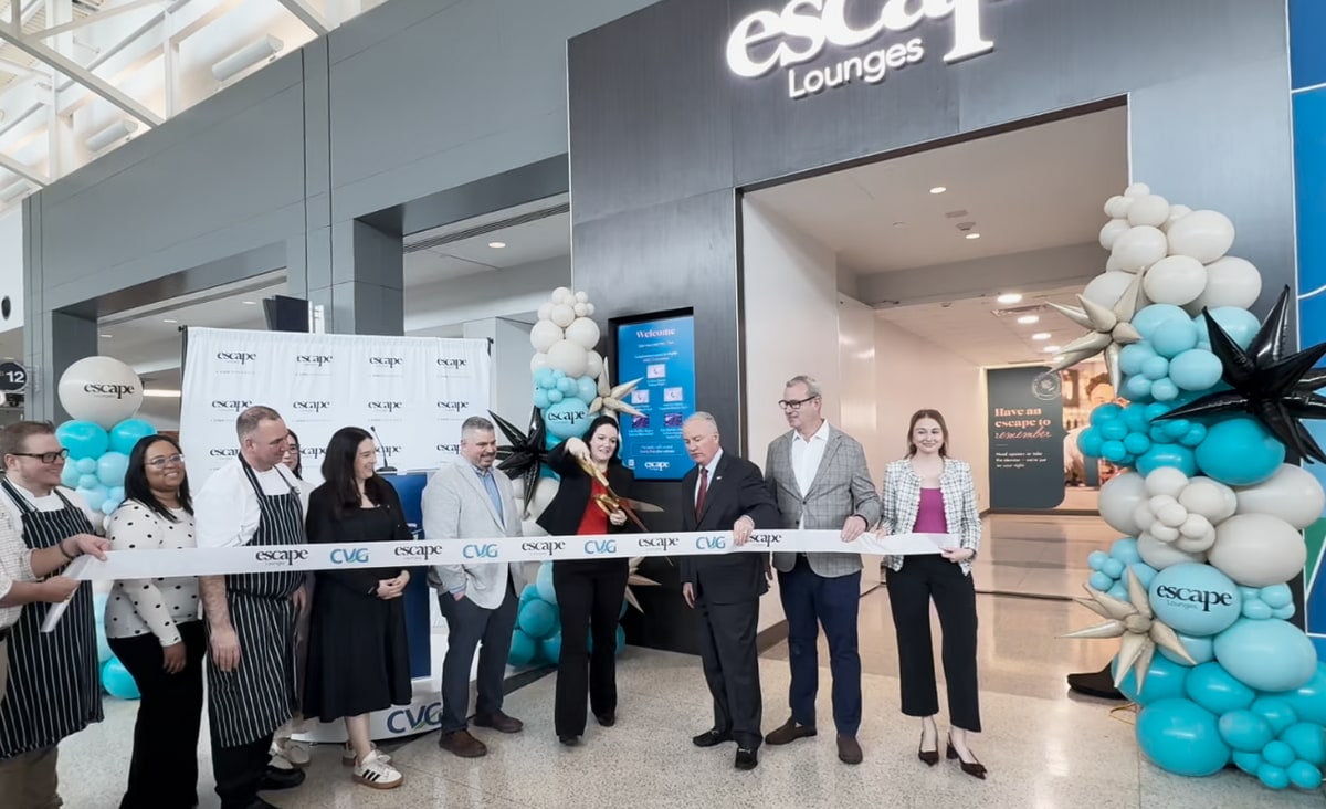 People holding a grand-opening ribbon with a person about to cut the ribbon.
