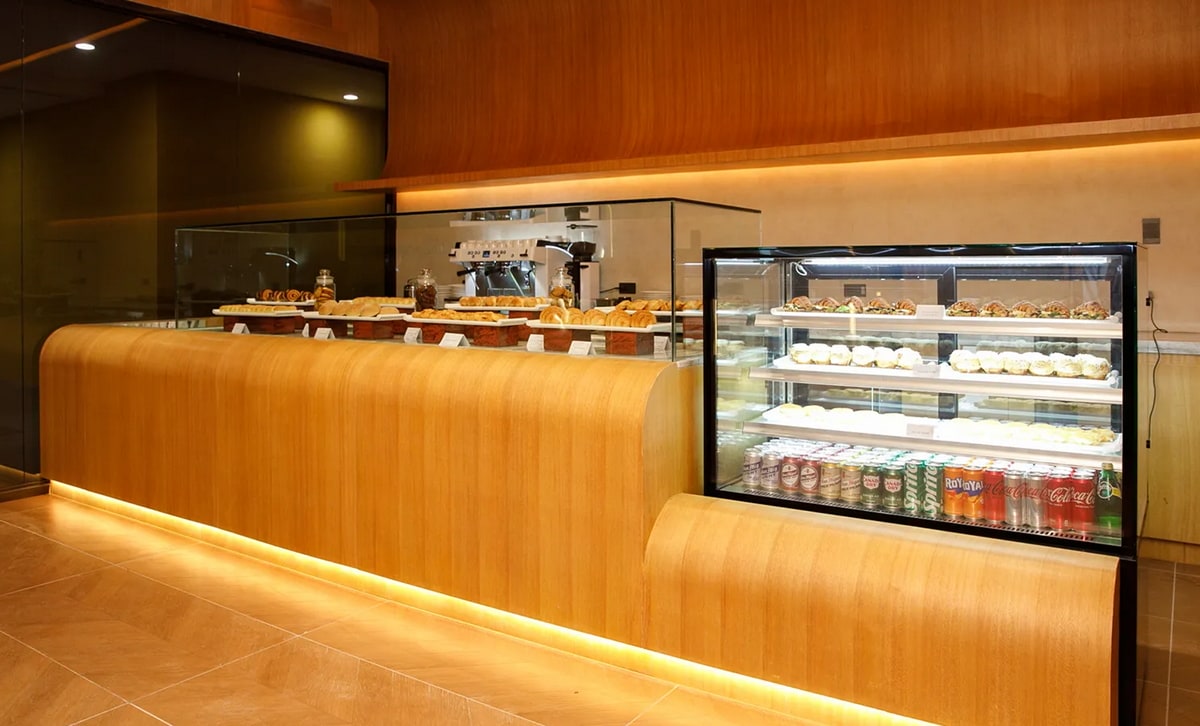 bakery room with fresh made baked items in a glass counter, as well as drinks and a coffee station behind counter.