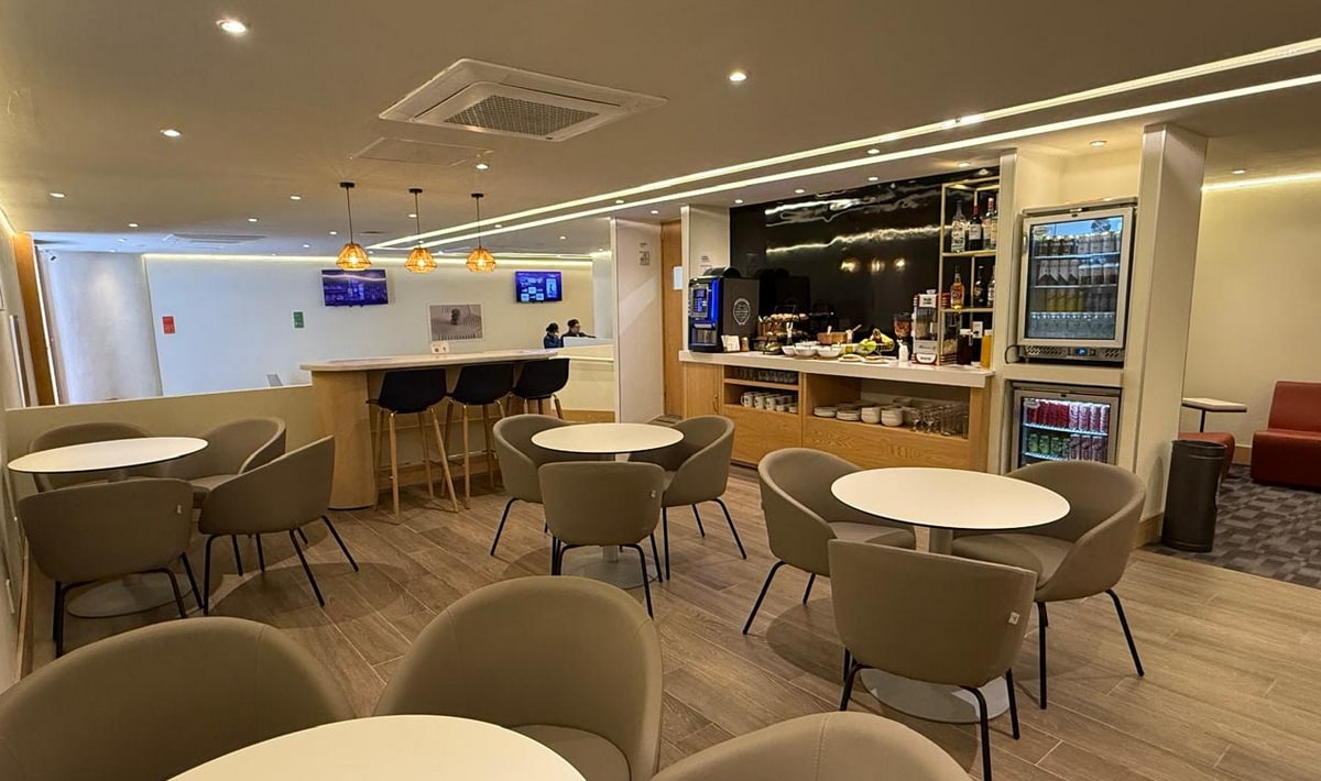 main seating area inside the Harmony Lounge with tables, seating, TVs, and a central area with food and beverages.