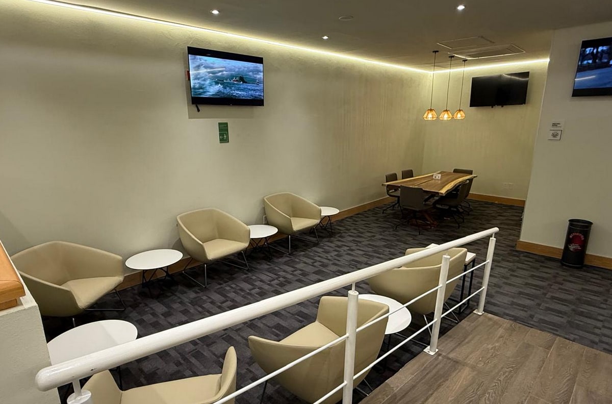 seating area with small side tables, TVs, and a conference table in the back corner of room.
