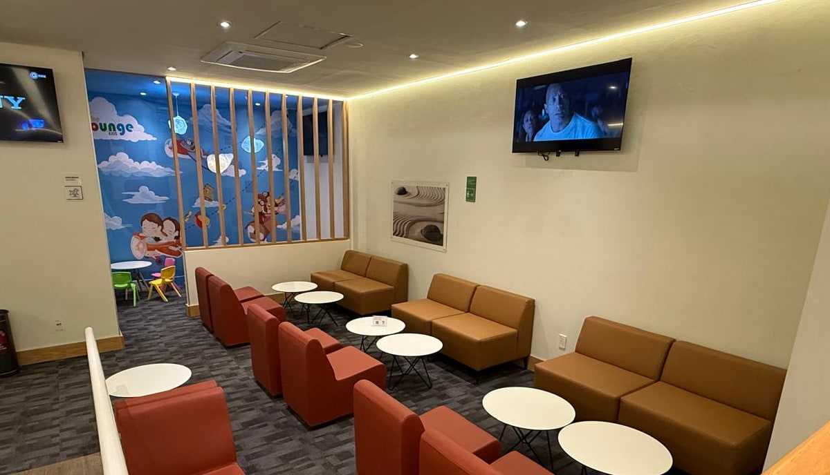 seating area with tables, chairs and a kids room in the back, with TVs on the wall.
