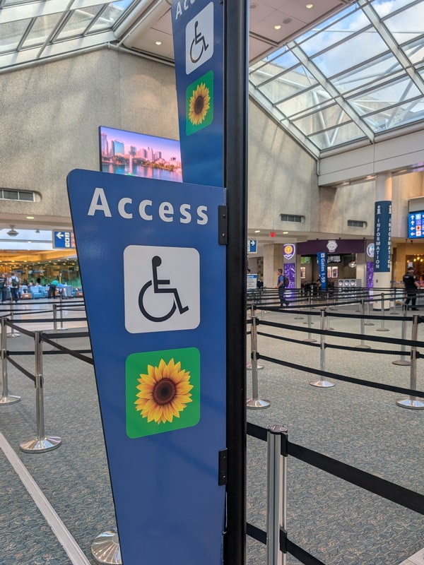 Sign in TSA secutiry area with wheelchair and Sunflower logo at Orlando airport.