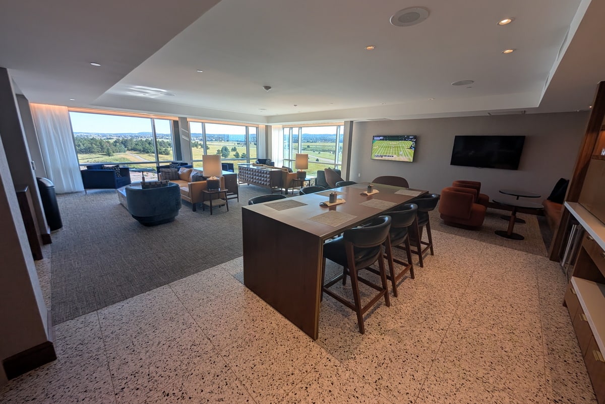 Tables and seating options inside the lounge, with TVs, large windows in the background.