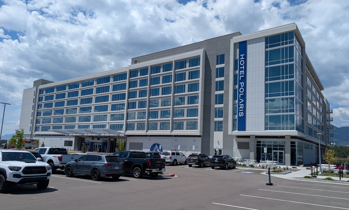 Outside view of the front of the Polaris Hotel from the parking lot during the day.