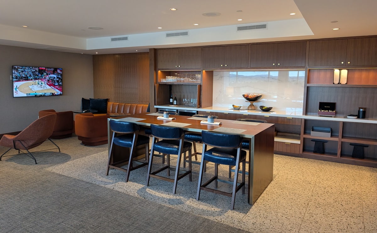 Seating area with leather chairs and tables, in the backgorund is a drink and snack serving area.