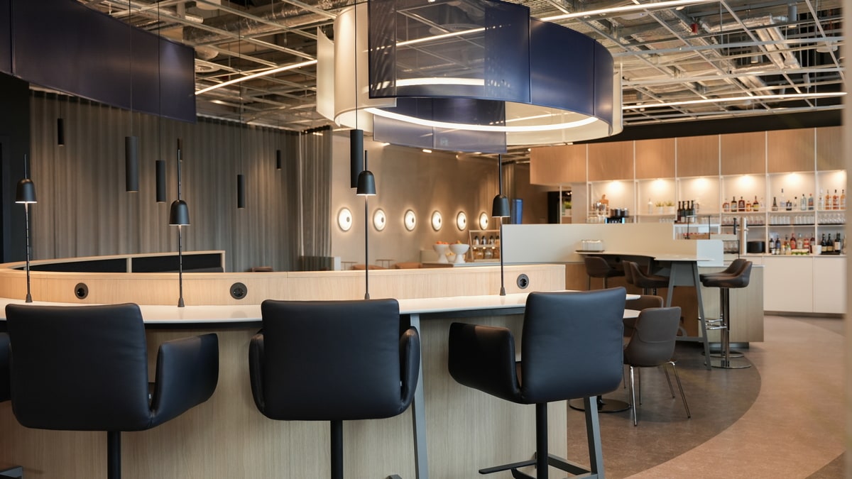 seating area with tables, and chairs, in the background is a self-serve area including bar.