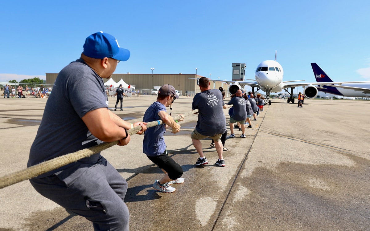 people pulling a plane, with a rope.