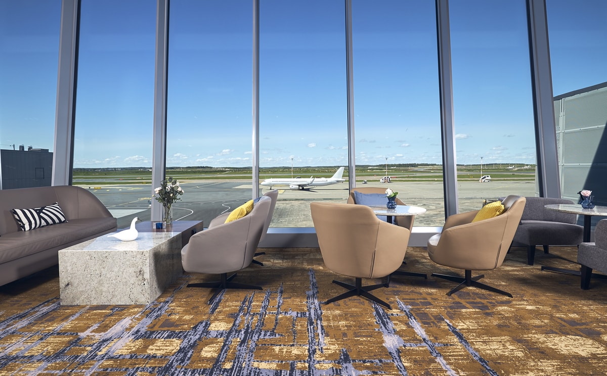 large floor-to-ceiling windows with view of the airfield and gates.