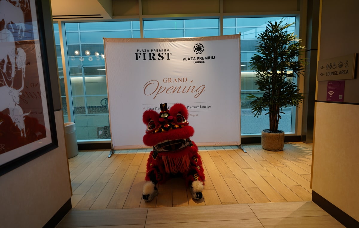 Dragon sitting on the floor in front of a Plaza Premium Lounge grand opening sign.