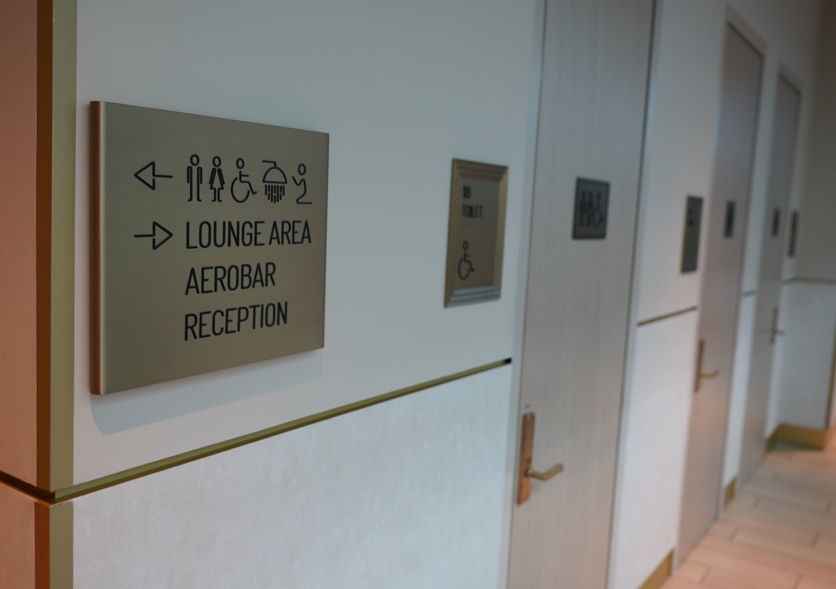 outside view of the restrooms, with a sign showing more restrooms around the corner.