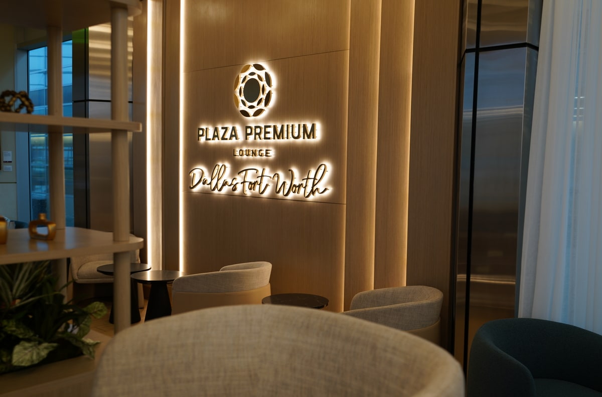 Backlight Plaza Premium Lounge Dallas Fort Worth sign hanging on wall with seating around.