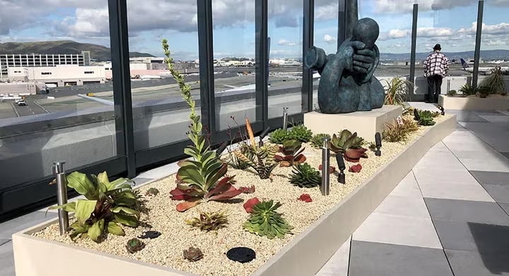 patio with glass, and sculptures with a person looking at airplanes.