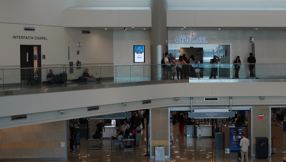 View from outside The Club Lounge in Atlanta (ATL) with people standing and sitting, waiting for their turn.