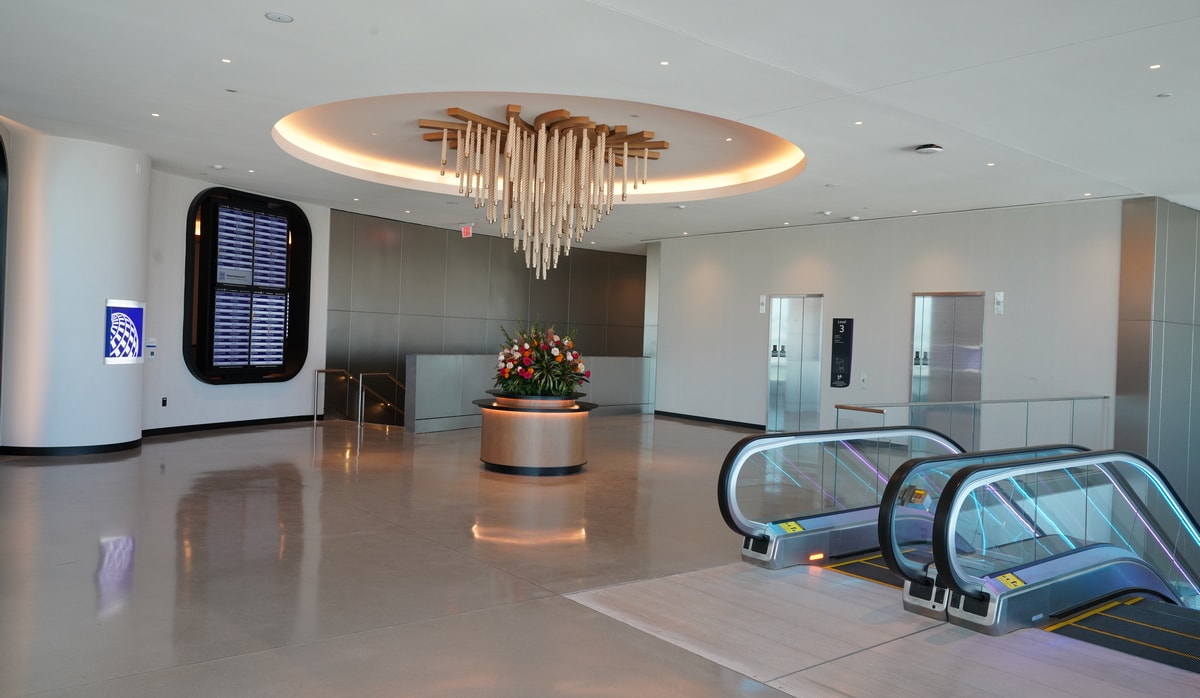 lobby area with flight monitors, elevator access, and art hanging from the ceiling.