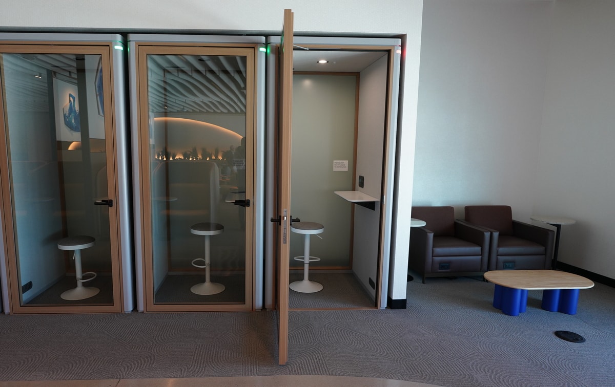 Phone booths with clear windows and corner seating area.