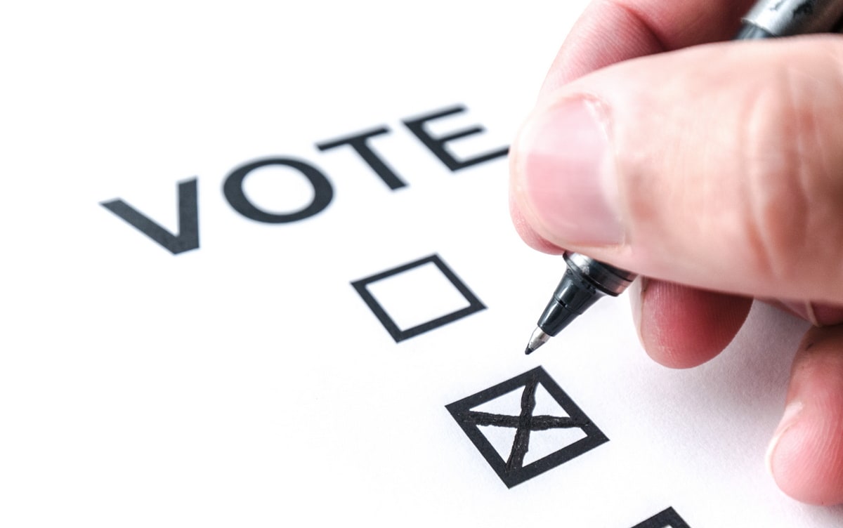 hand marking a vote box on paper with pen.